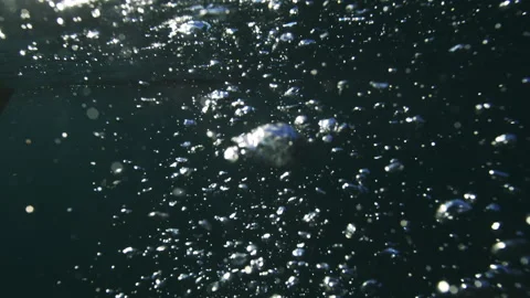 Air bubbles churning below rippling ocean surface with bright highlights Stock Footage 345339808