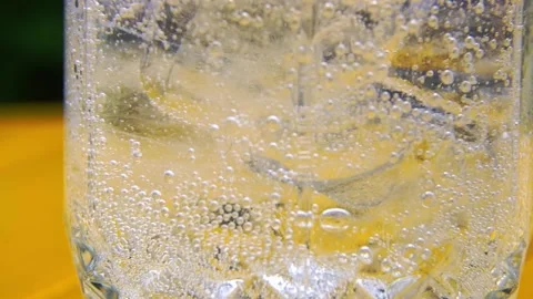 Air bubbles in a glass with ice cubes and tonic water Stock Footage 153698995
