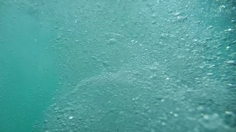 Air bubbles rise in clear blue water with tiny particles swirling around, c.. Video stock 252065031