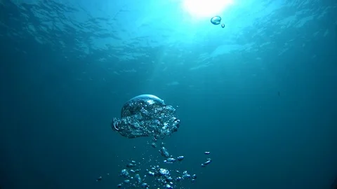 Air bubbles rise to the surface of blue water in the rays of the sun,  slowmo Stock Footage 124218734