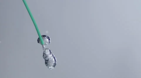 Air bubbles shoot out of a green straw in clear liquid w/ white BG. Stock Footage 64891560