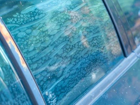 Air bubbles trapped in old deteriorated car window tint film, damaged adhes.. Stock Photos