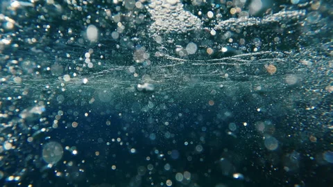 Air bubbles under seething surface of waves at sunset, underwater shot Stock Footage 252031158