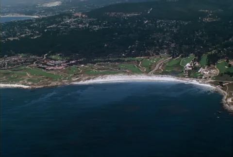 From the air, the camera parallels the white, sandy coastline of Spanish Bay Stock Footage 86773145