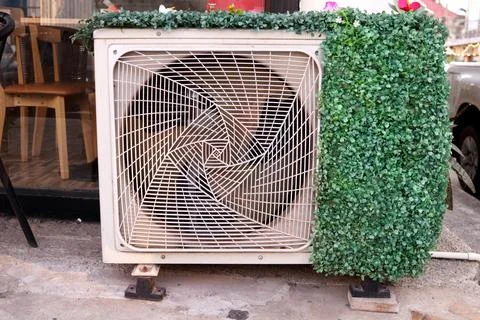 Air condition compressor covered artificial plant. Stock Photos