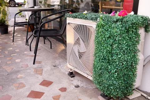 Air condition compressor outside with artificial plant. Stock Photos