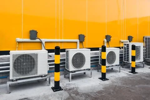 Air conditioner compressor installed outside building with yellow and black w Фото