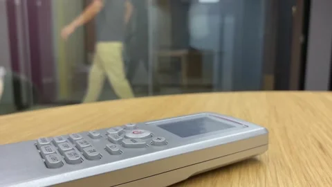 Air conditioner controller on wooden table. Blurred male worker walking outside Stock Footage 251283153