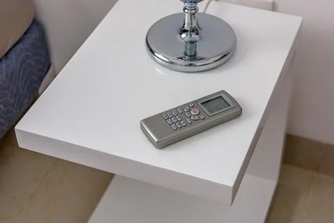 Air conditioner remote control on white bedside table Stock Photos