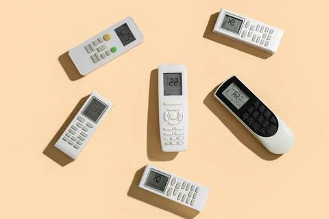 Air conditioner remote controls on beige background Stock Photos