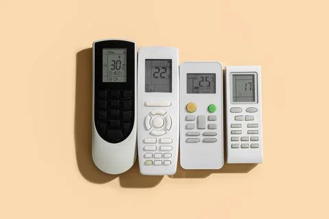 Air conditioner remote controls on beige background Stock Photos