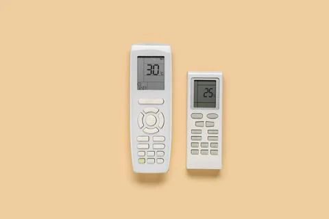 Air conditioner remote controls on beige background Stock Photos