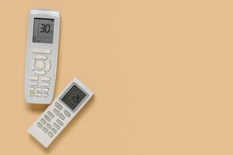 Air conditioner remote controls on beige background Stock Photos