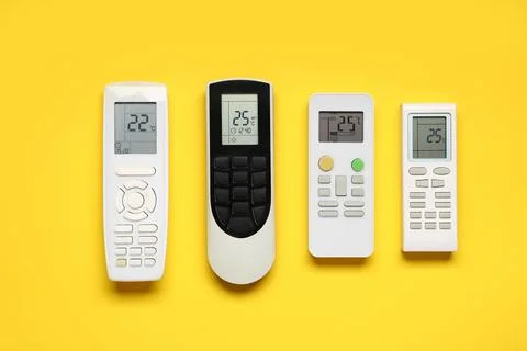 Air conditioner remote controls on yellow background Stock Photos