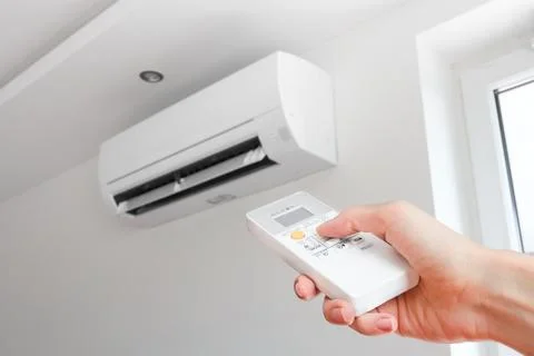 Air conditioner temperature adjustment with remote controller in room at home Stock Photos