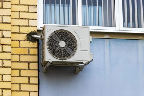 An air conditioning system installed outside on the wall of a brick building. Photos
