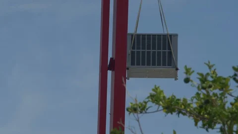 An air conditioning unit being lifted to a rooftop by a crane Stock Footage 92924843