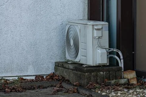 Air conditioning unit on concrete base beside building Stock Photos