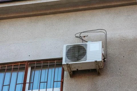 Air conditioning unit installed on a building exterior during summer season Stock Photos