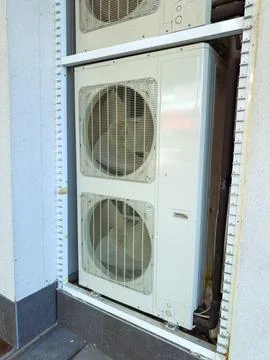 Air conditioning unit installed on a building exterior at a commercial loca.. Stock Photos