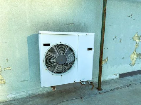 Air conditioning unit installed on a wall near a building Stock Photos