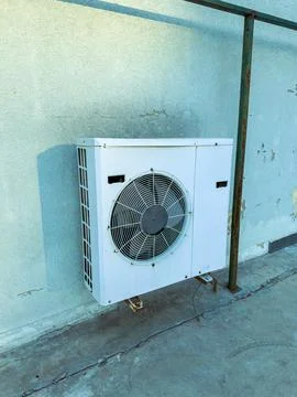 Air conditioning unit mounted on a wall in an urban outdoor setting during .. Stock Photos
