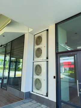 Air conditioning units installed on a building near a commercial area durin.. Stock Photos