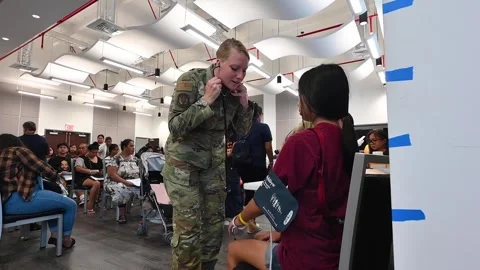 Air Force medics fitting blood pressure arm cuff at wellness clinic in Guam Stock Footage 281062589