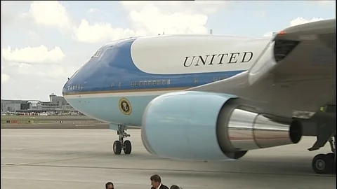 Air Force One  - pullout from wheel to reveal plane preparing to approach runway Stock Footage 73398894