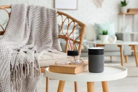 Air humidifier with book and reed diffuser on coffee table in living room Stock Photos