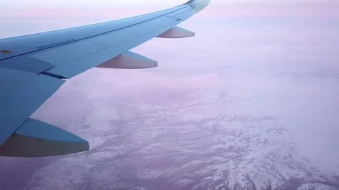 Air plane flies among the clouds over snowy capped mountains. Stock Footage 143372079