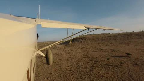 Air plane side view flying low over dry savannah at morning Stock Footage 310978496