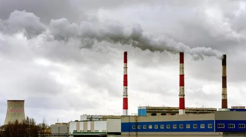 Air pollution from smoke coming from three factory chimneys. Stock Photos