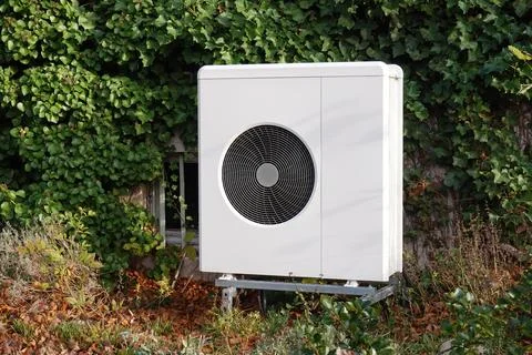 Air source heat pump in front yard for heating and cooling residential building Stock Photos