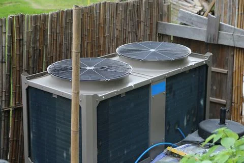 An air source heat pump with two large round fans on top, set against the b.. Stock Photos