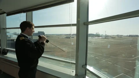 Air traffic controller is looking into distance in airport with binoculars Stock Footage 65739442