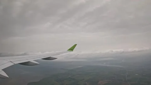 AirBaltic airplane descending below clouds over coastline and fields Stock Footage 340320572