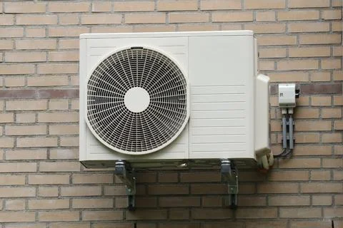 Airconditioning unit installed on brick wall. Stock Photos