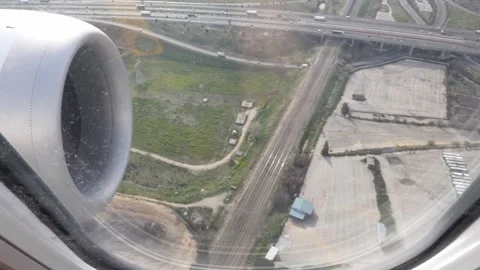 Aircraft engine from a passenger window with traffic highway below during de Stock Footage 339353147
