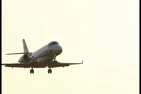 Aircraft flying through sun rays at dusk low above airport Stock Footage 27343098