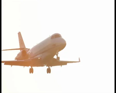 Aircraft flying through sun rays at dusk low above airport Stock Footage 30078663