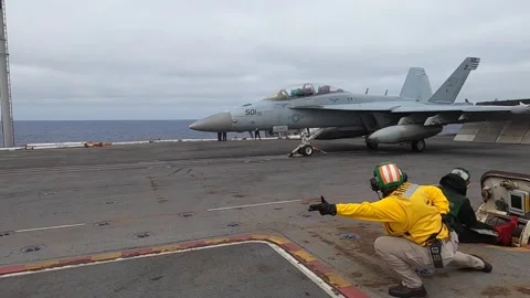 Aircraft handler signalling to F/A-18 Hornet pilot taking off from USS Nimitz Stock Footage 280385764