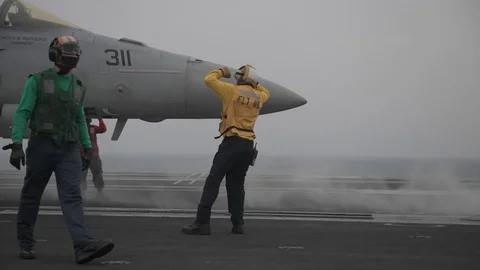 Aircraft handler signals to pilot of F/A-18 Hornet aboard USS John C Stennis Видео 101373874