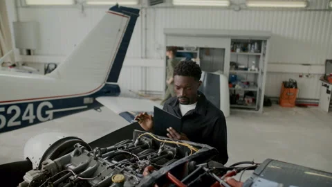 Aircraft Inspector Examining Airplane Engine and Taking Notes in Hangar Stock Footage 310849811