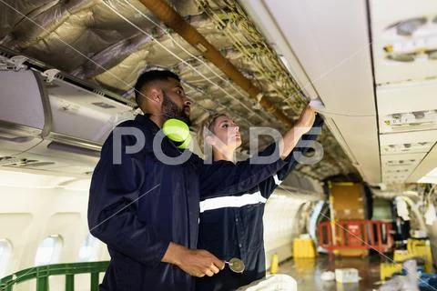 Aircraft Maintenance Engineers Working Over Internal Structure Of An Aircraft