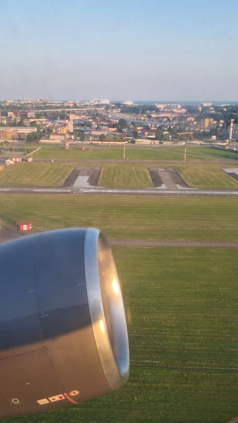 Aircraft passenger window framing dramatic coastal takeoff, landscape spreading Stock Footage 314322538