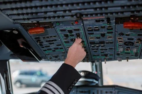 Aircraft pilot operating overhead panel of airplane flight deck Stock Photos