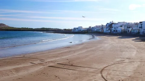 Aircraft taking off next to an empty beach in front of a small village Video stock 137268198