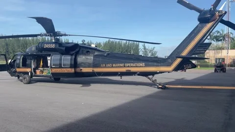 Aircraft tug pushing Customs Border Protection UH-60 Blackhawk on airfield Stock Footage 290334985