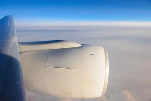 Aircraft window into jet engine with blue sky Stock Photos